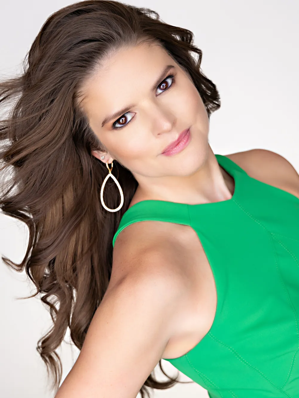 Lindsey Elmore in a green dress, hair swept to one side, against a white background